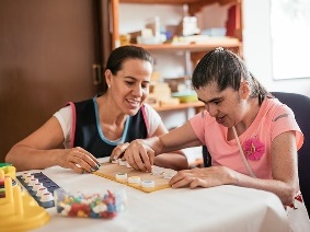 A woman helping a girl do an activity.